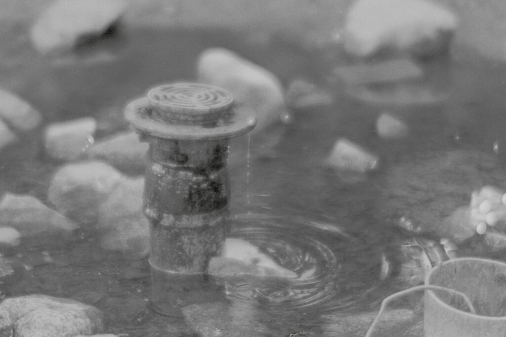 Drainpipe in a pool of water, surrounded by rocks.