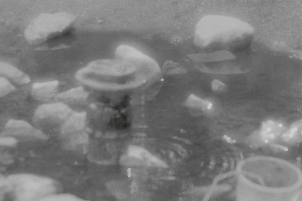 Drainpipe in a pool of water, surrounded by rocks.