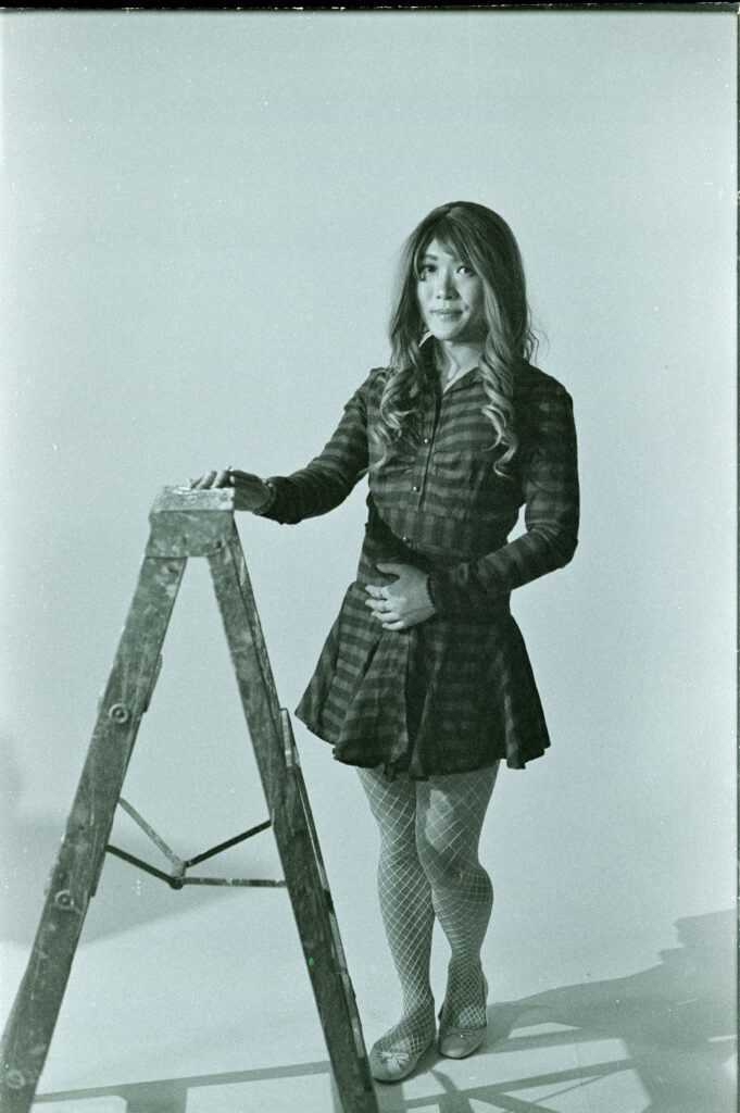 Lily standing next to a ladder on white background in black and white with a green tint