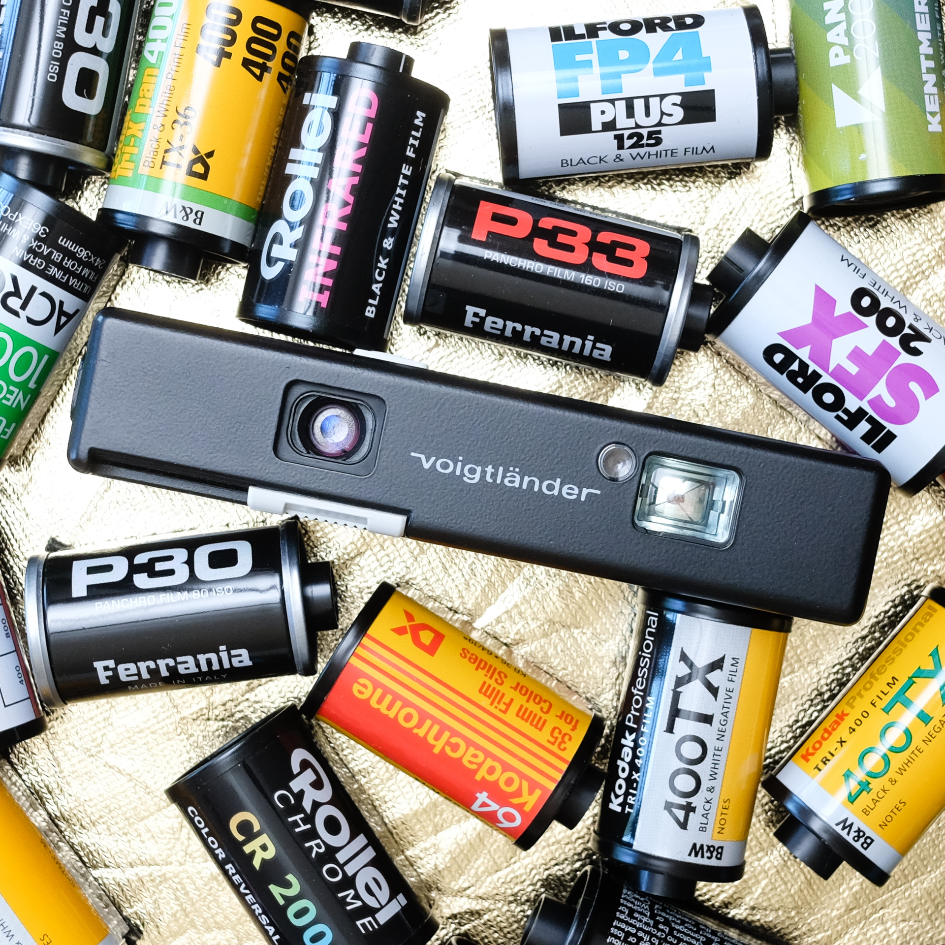 Voigtlander Vitoret 110 EL camera from the front surrounded by 35mm film canisters