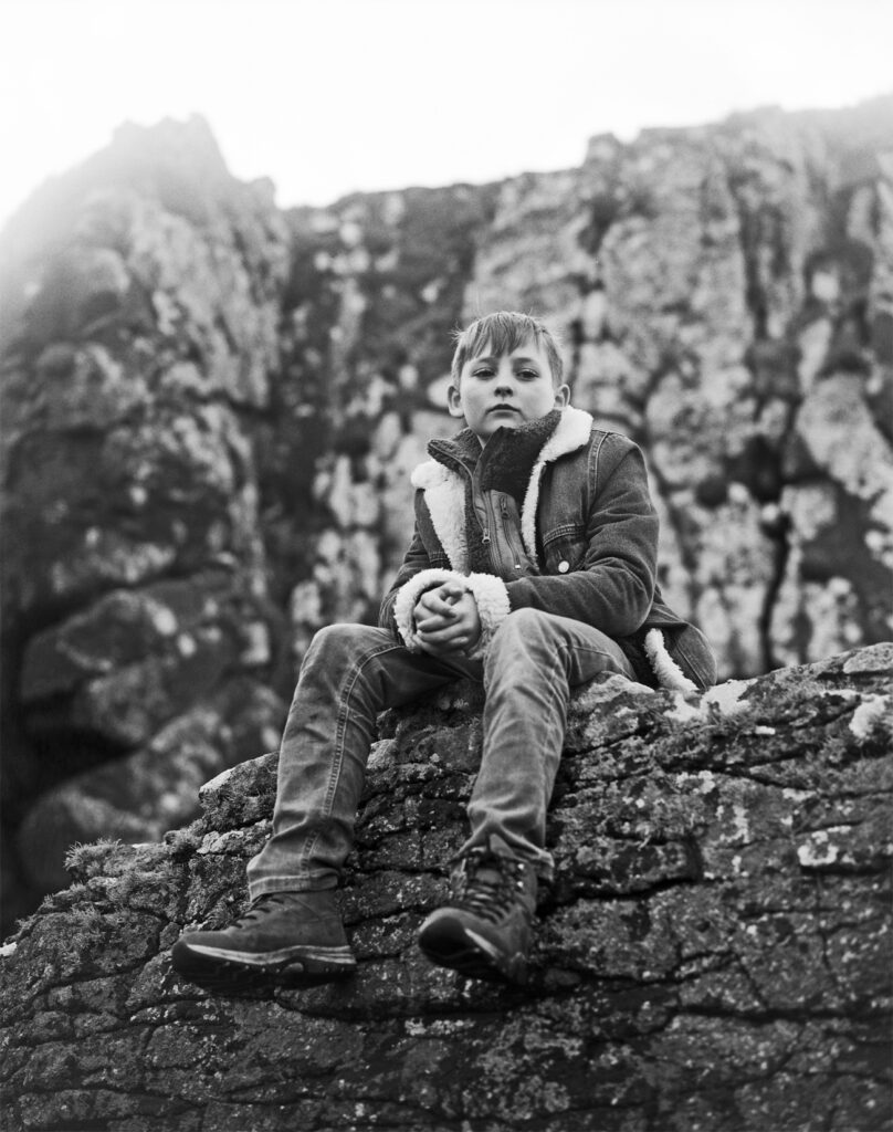 Isaac sits on rocks at the beach