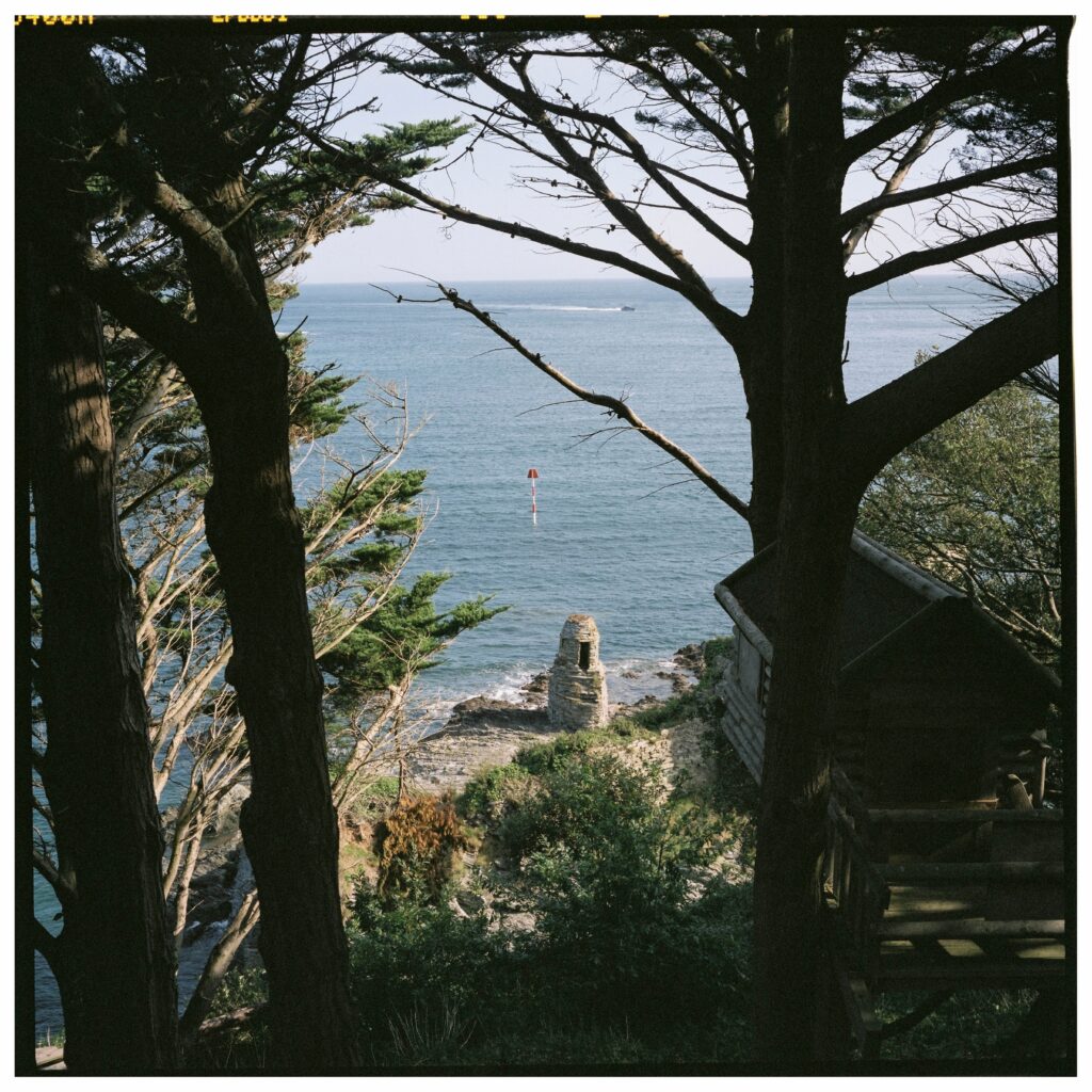 An stone structure on the coast on Salcombe, viewed between trees.