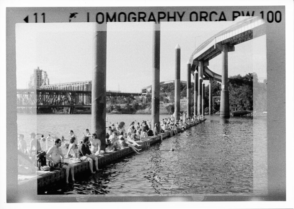Black and white photo of swimmers sitting on a dock