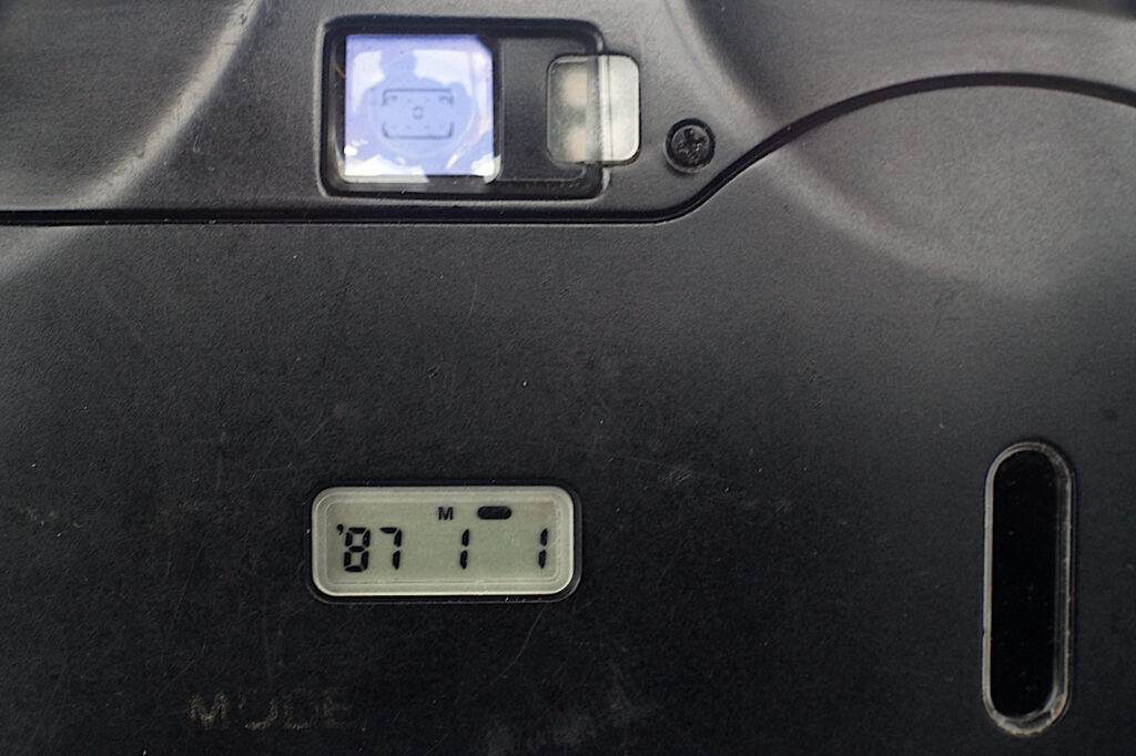 Detail of the back showing the date setting panel and buttons, and the finder and the adjacent warning lights.