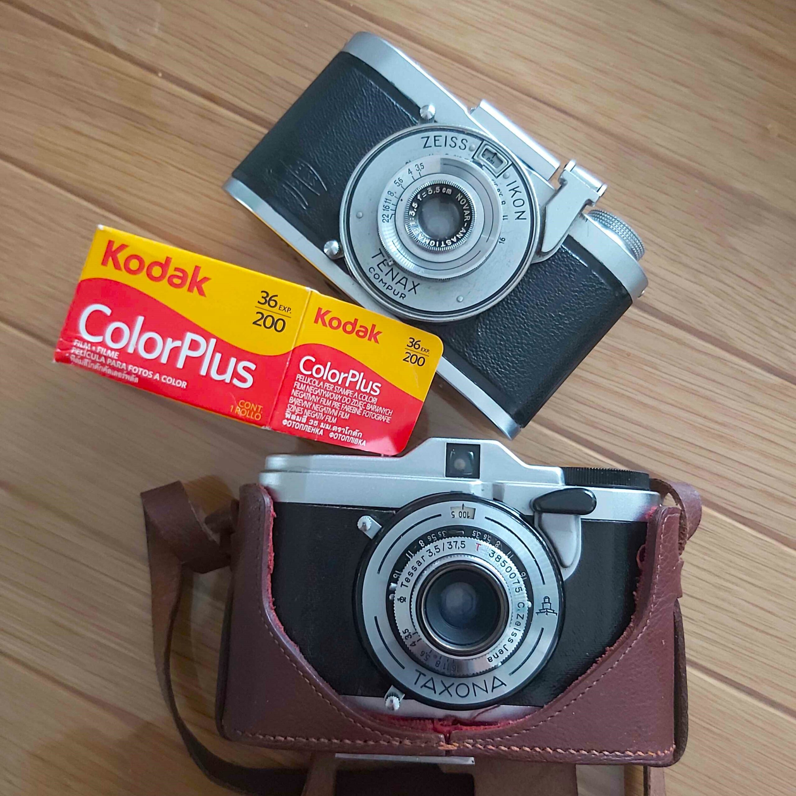 A Zeiss-Ikon Tenax I, a box of Kodak ColorPlus film, and a Zeiss-Ikon Taxona in its leather case.