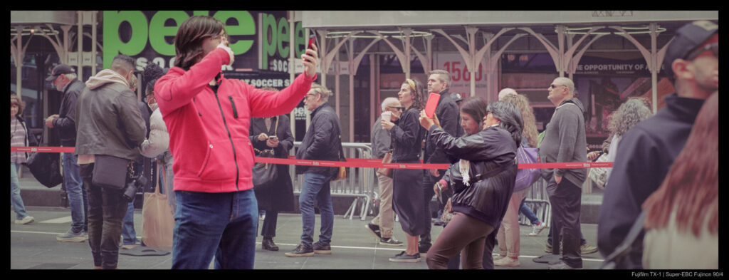 Two people take simultaneous photos in Times Square.