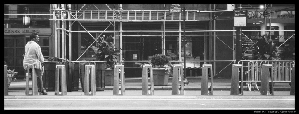 A person sits on the left atop a series of Citibike docks which march across the frame.