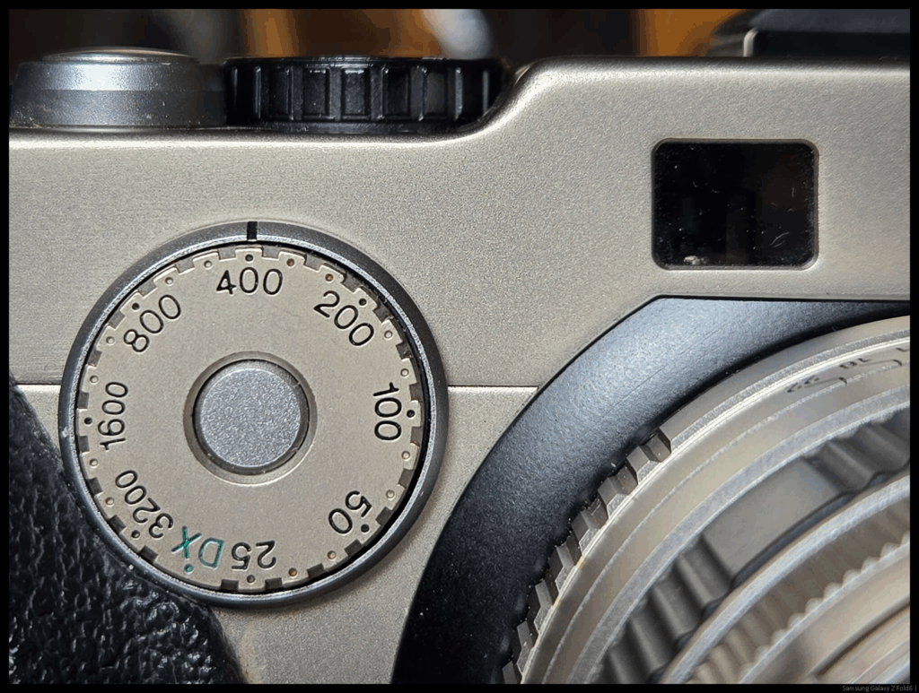 A close up of the Fujifilm TX-1 ISO dial, with the setting at 400. Part of the lens barrel and the rangefinder window are visible.