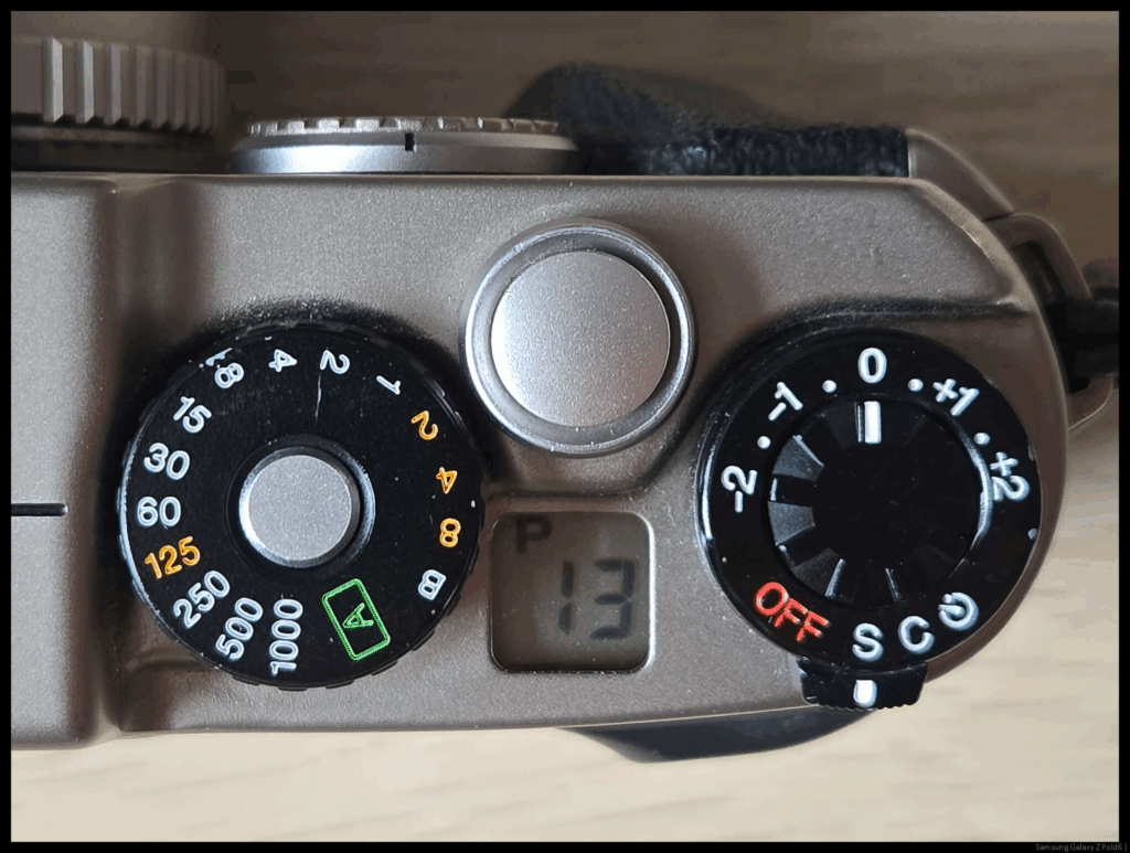 An image of the top deck of the Fujifilm TX-1, displaying various controls and the remaining frame count.