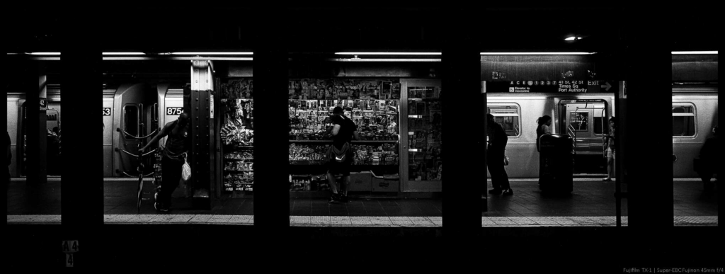 An image of a subway platform in Times Square viewed through a series of structural pillars that create the appearance of a filmstrip of small square images.