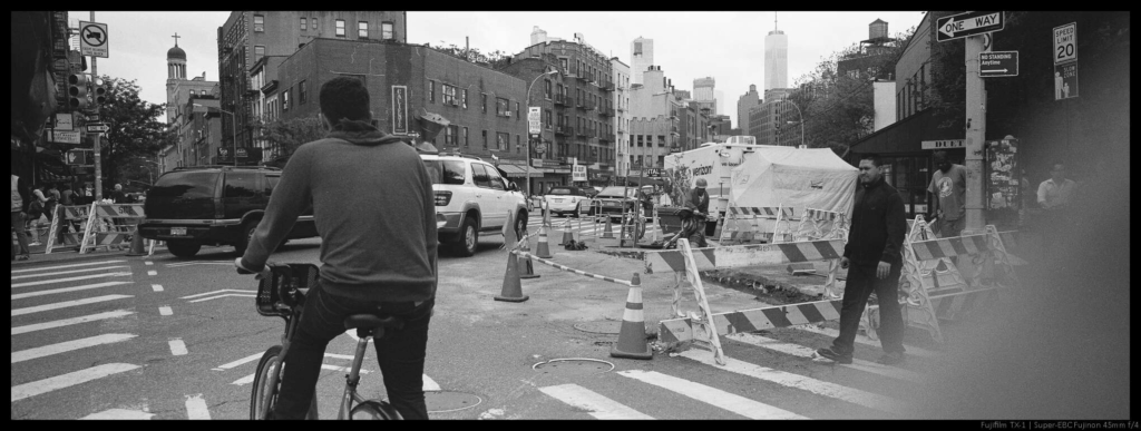 An image of a crowded intersection partially obscured by a blurry finger in the corner of the frame.