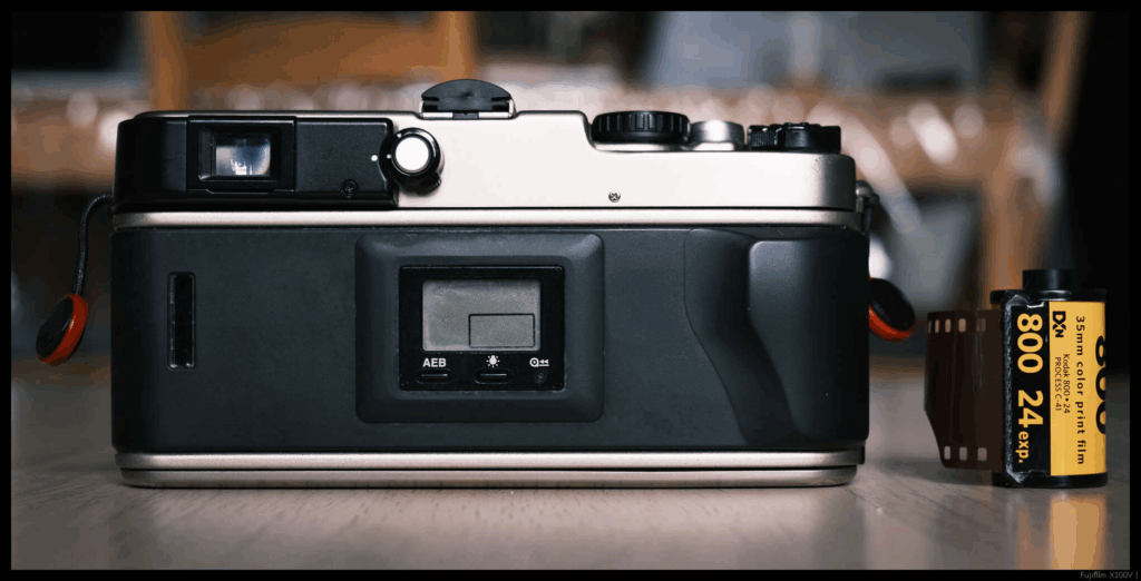 An image of the back of the Fujifilm TX-1, with a 35mm cassette placed to the right.