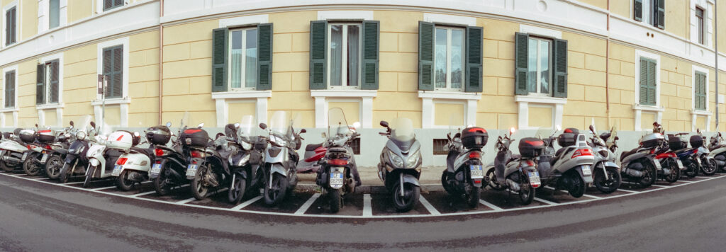A wide format photo of a row of tightly parked moped motorcycles