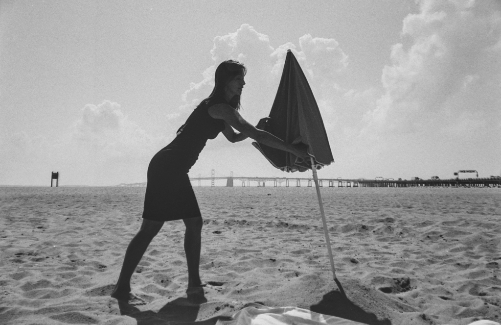 A silhouette of an actor and umbrella on a beach.