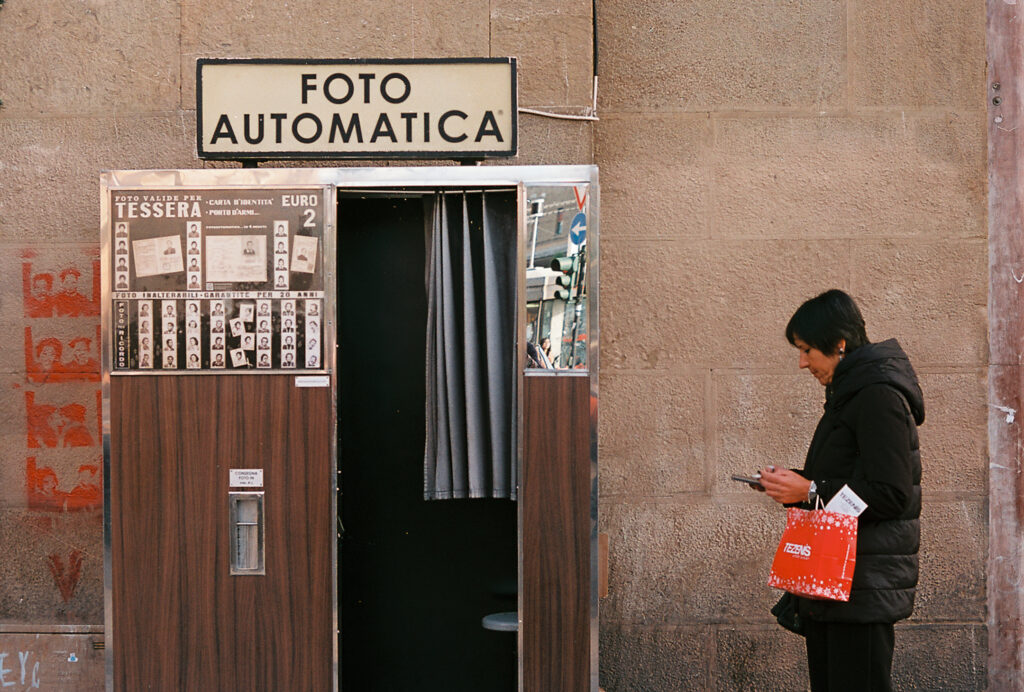 A lady stopping to check her phone next to a vintage photobooth