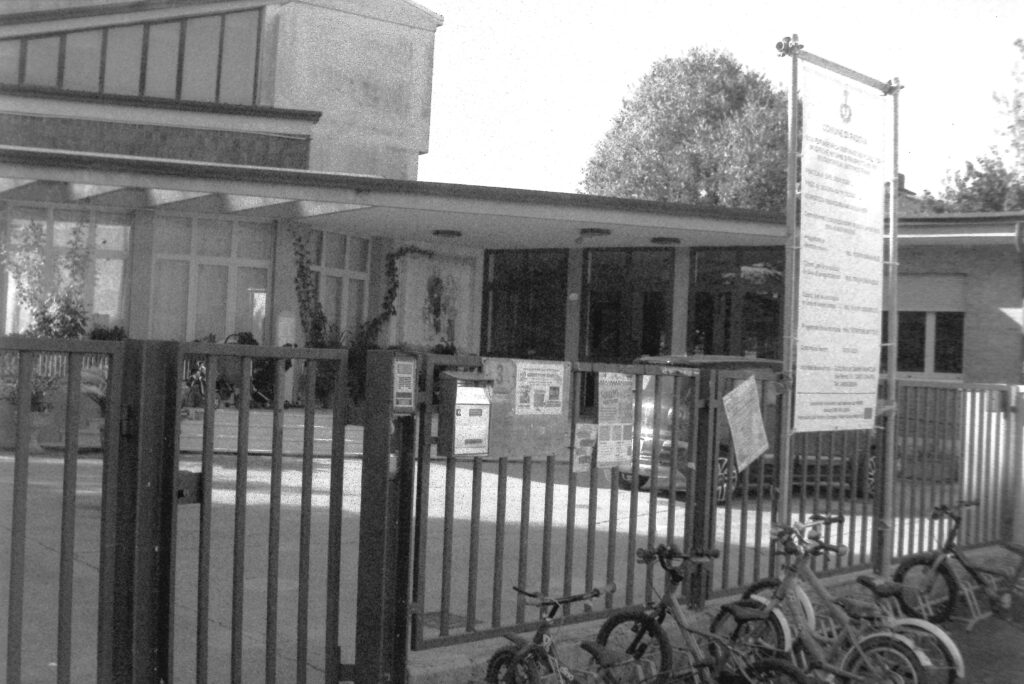 A nursery school, with some small bicycles on the fence.