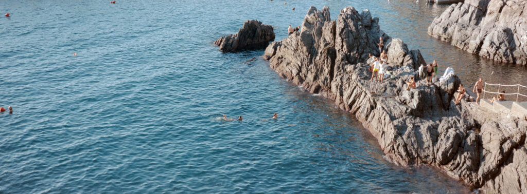 People sitting on the rocks in Italy on a summer day shot on the Hasselblad Xpan and shot by Tom Kluijver