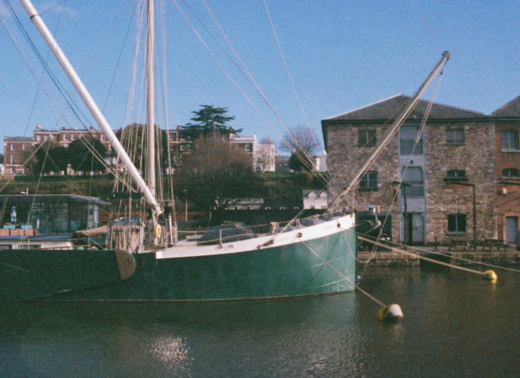 Sailing boat moored on the quayside with old warehouses in the background