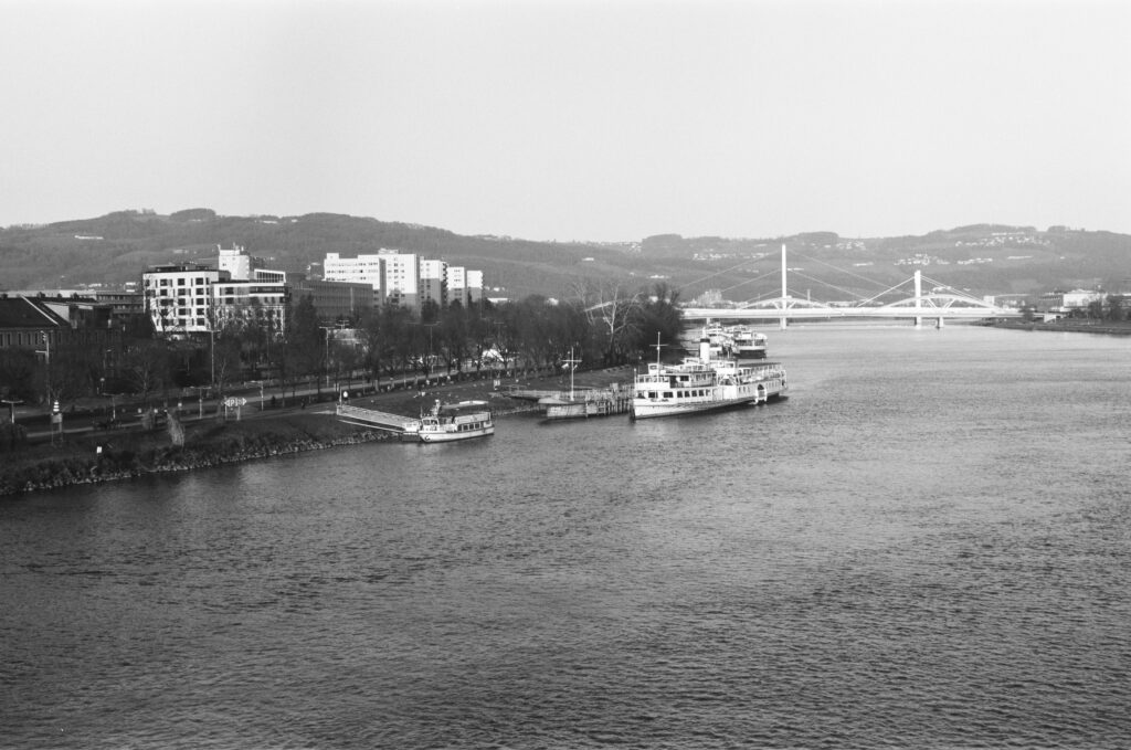 View downstream from Nibelungen bridge, river bank of River Danuve with a steam paddler mored to the quai