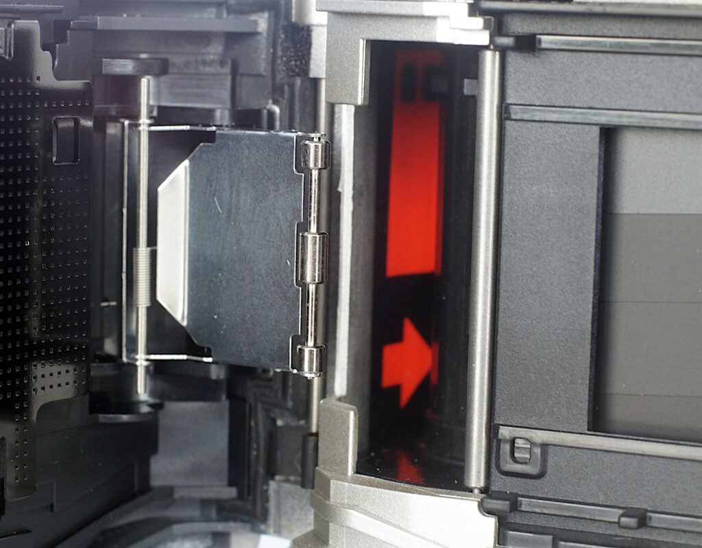 Film leader insertion point and “bailing arm” that presses the film down onto the take up drum.