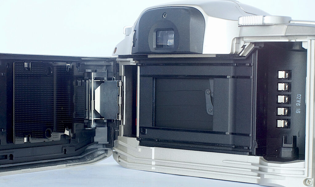 Back open. Film passing from right to left. DX-coding contacts visible in the cassette chamber.