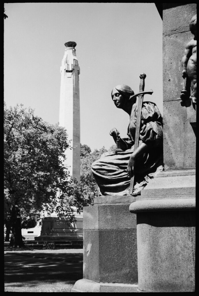 The Cenotaph and one of the bronzes at the base of Queen Victorias monument in Queen’s Gardens, Dunedin.