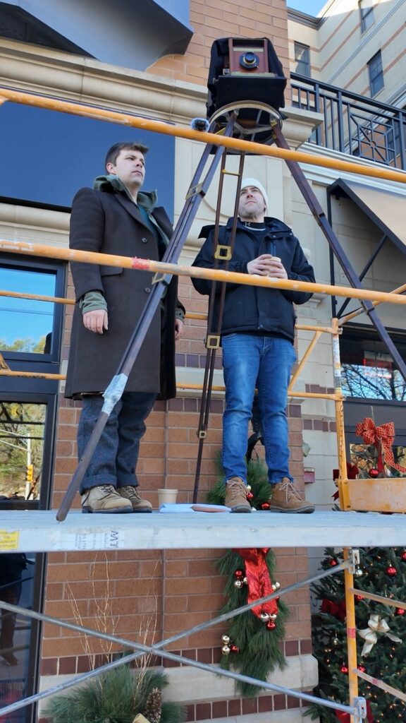 Two photographers operate a Cirkut camera on the scaffolding.