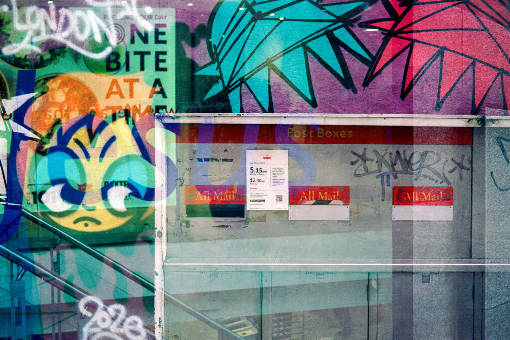 Double exposure featuring Royal Mail postboxes and graffitied walls.