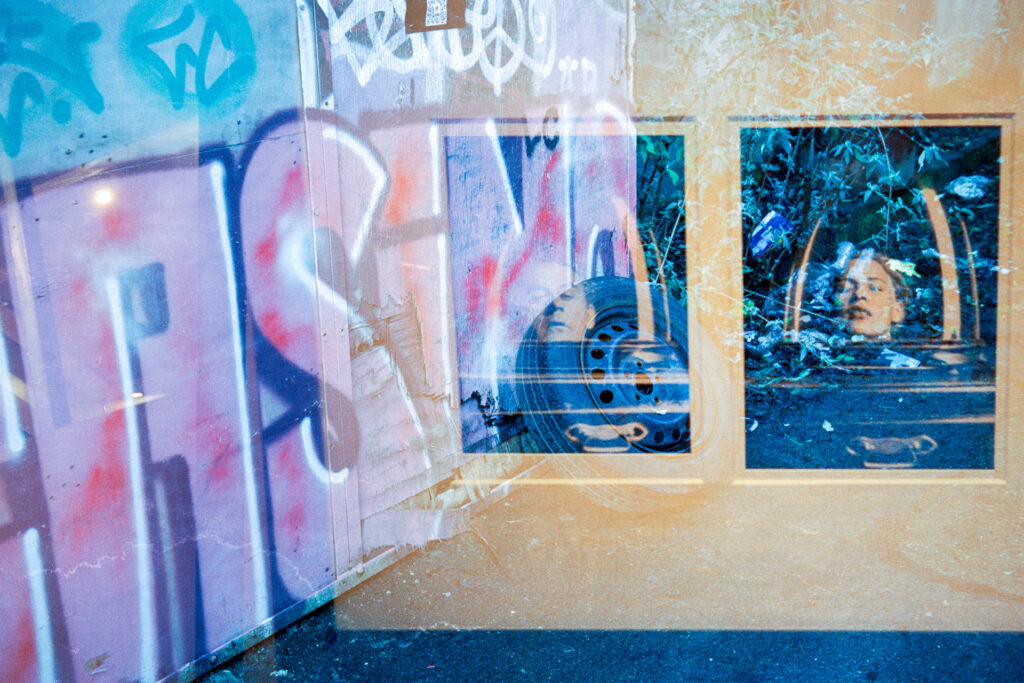 Double exposure on 35mm film featuring a graffitied wall and dumped car tire over layered with a gallery wall framed photo of Man Ray and Lee Miller from the Lee Miller Exhibition at Tate Britain. 