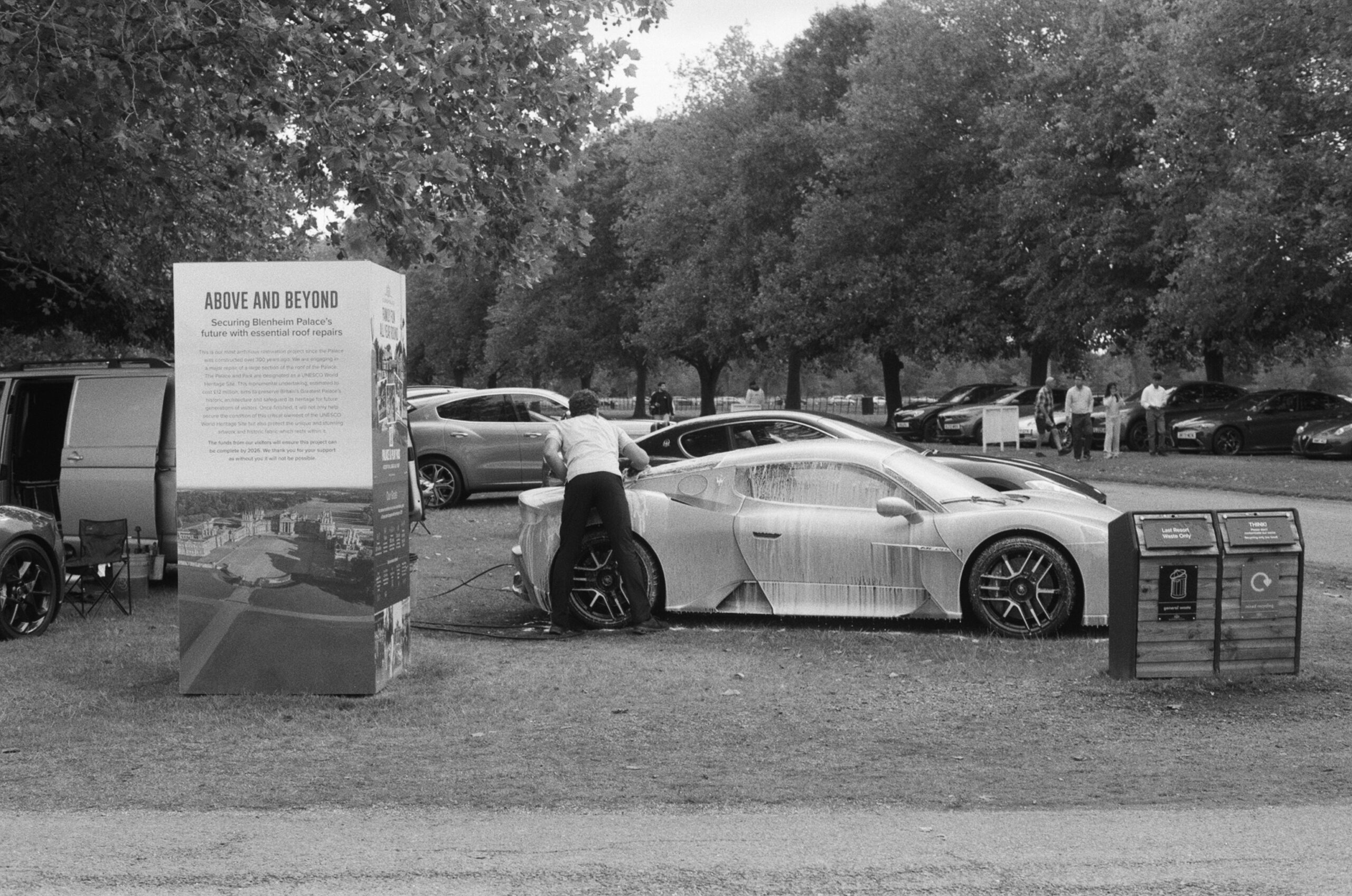 A man is washing a high performance car next to an information panel with the title Above and Beyond