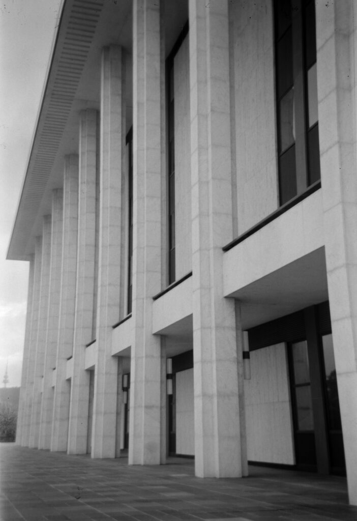 Black and white photo of the large stone columns of The National Library of Australia. 