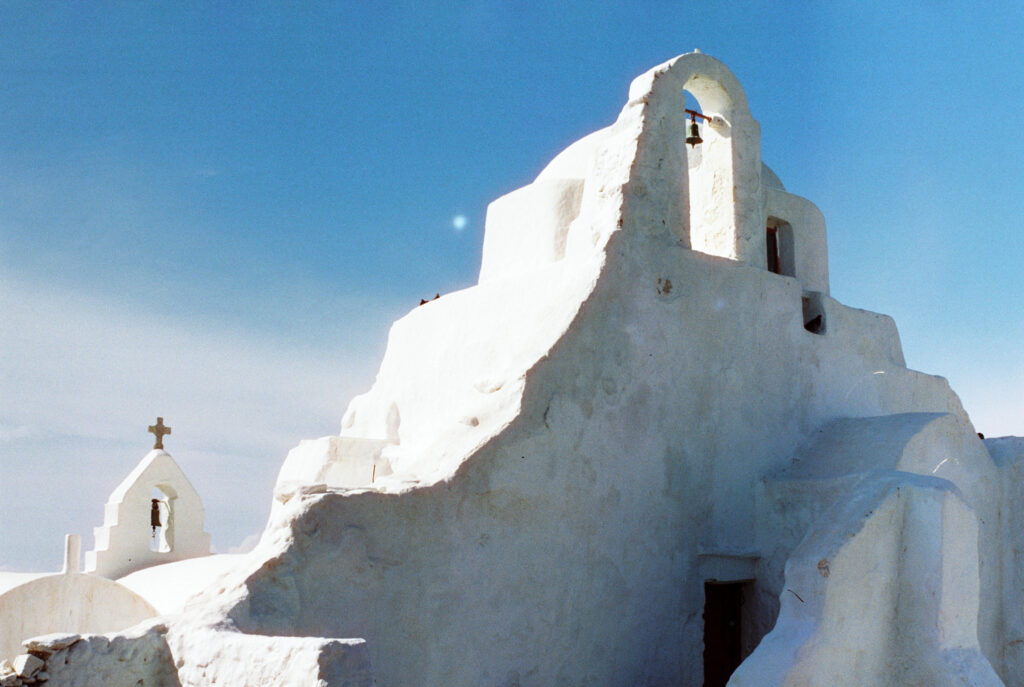 Sculpted white forms of the Panagia Paraportiani church against a blue sky