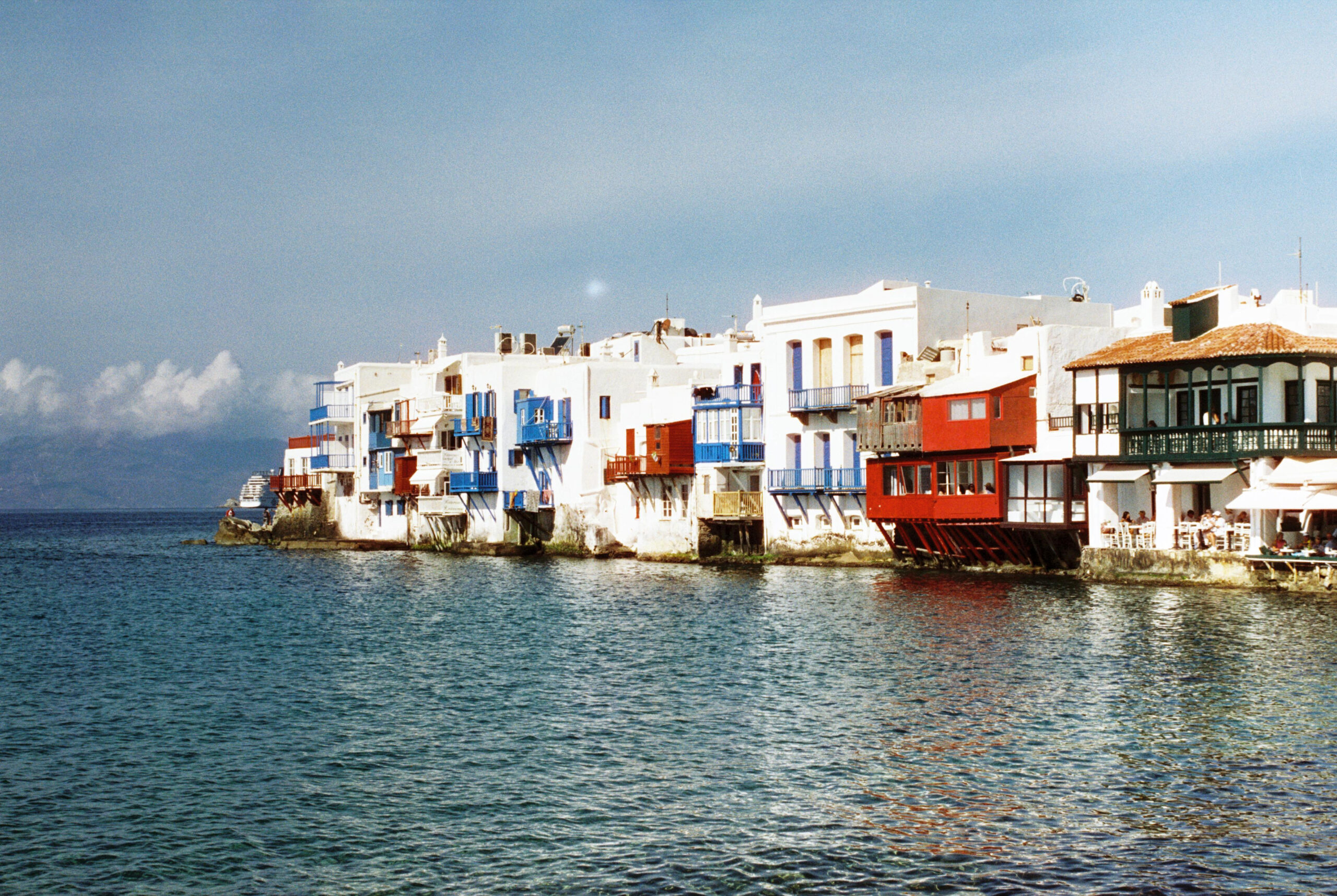 Painted houses of Little Venice in Mykonos seen from the water, late afternoon light