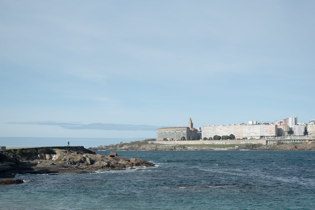 At the end of the breakwater, a person watches the ocean