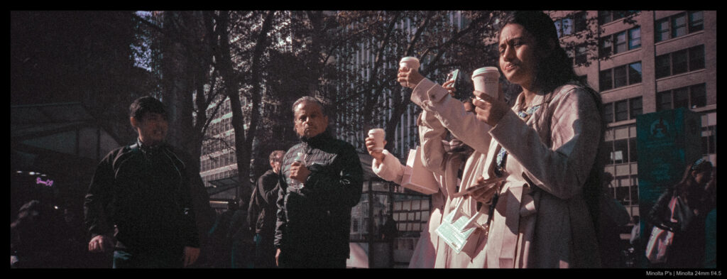 Three people hold their coffees up in the air to snap photos of their drinks.