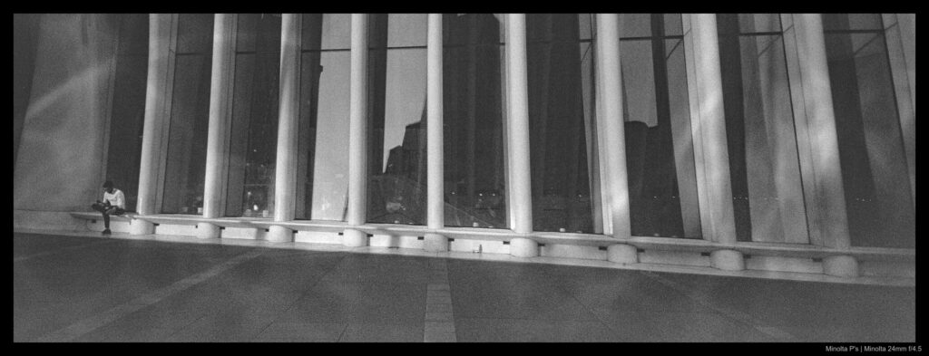 A person sits at the top of a sloped section of the Oculus, with its ribs starkly visible in a repeating pattern.