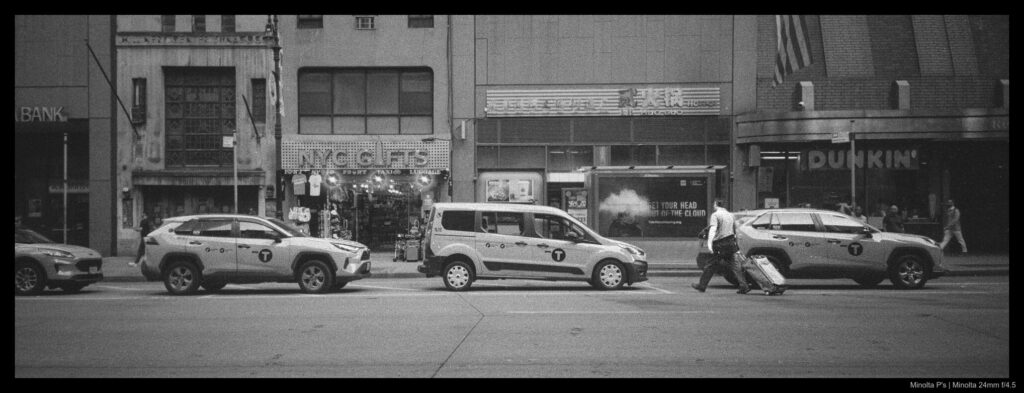 A person drags a suitcase behind them up to a line of waiting taxis, ready to go who-knows-where.