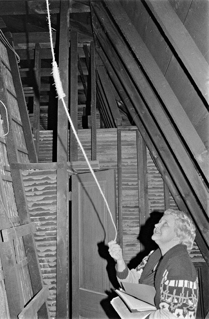 Woman holding a rope attached to coatroom ceiling