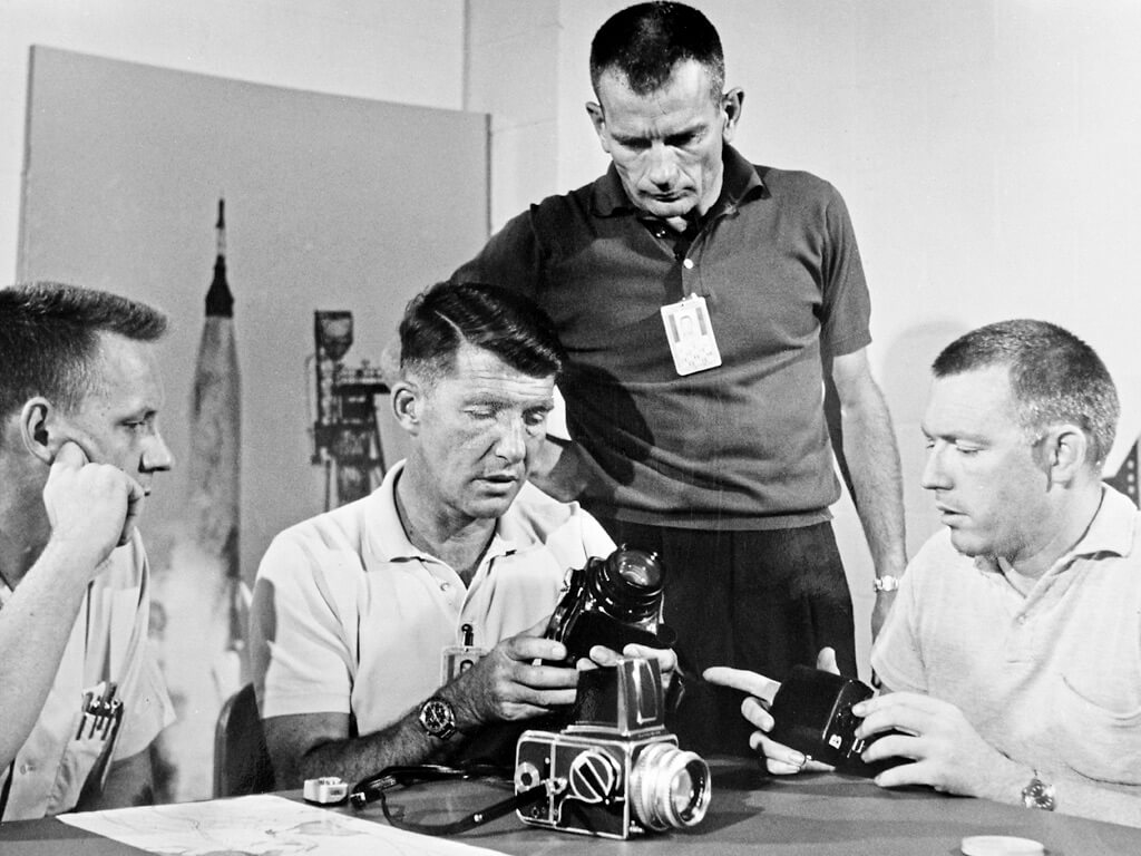 black and white photo of four men examining cameras