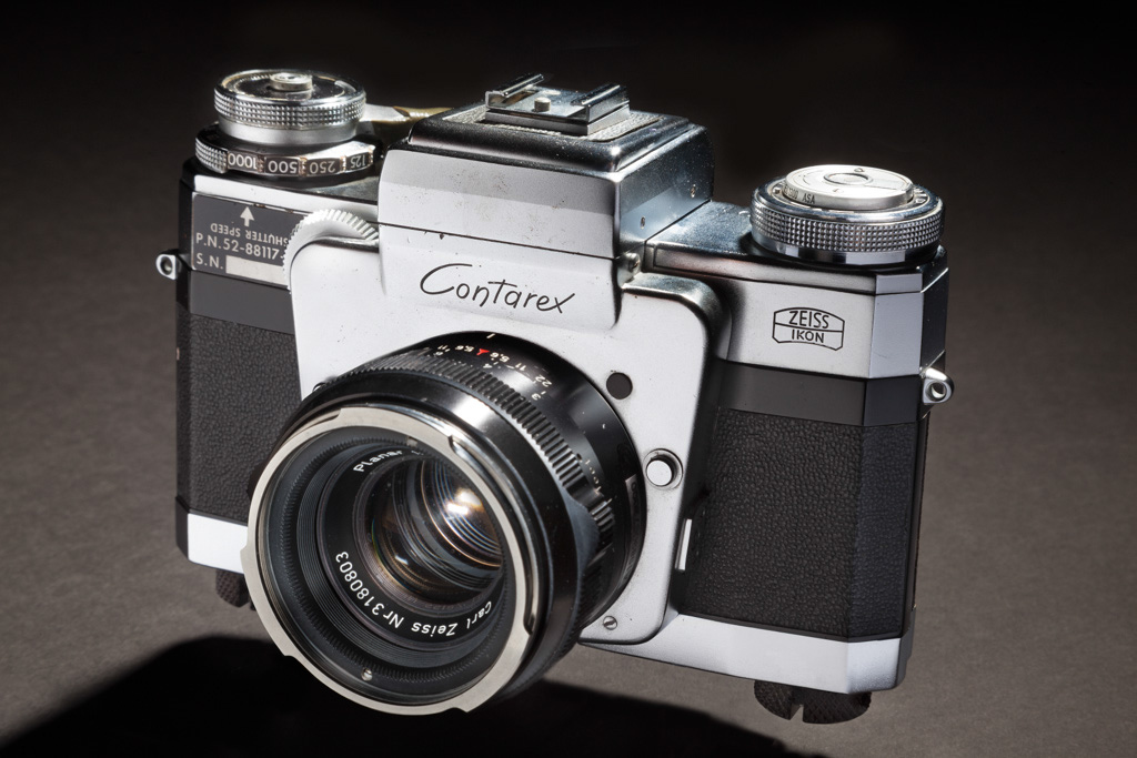 old silver metal and black leather camera with controls on top and a black lens