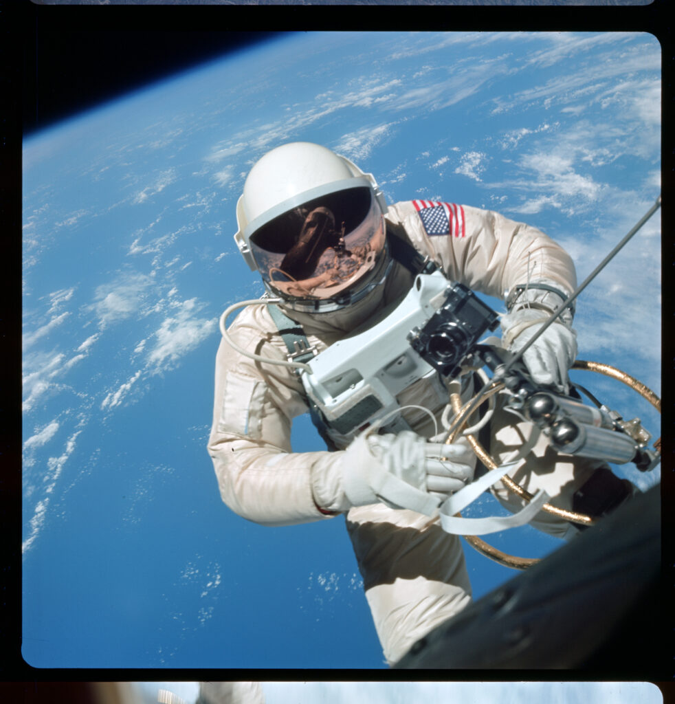 an astronaut doing a spacewalk in space while holding a camera and other equipment with the earth in the background