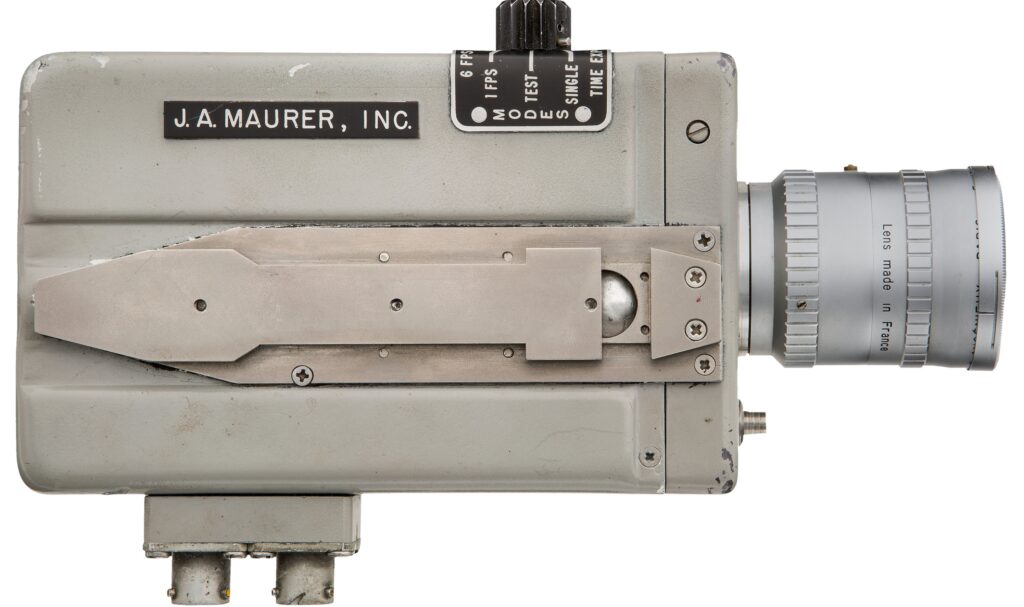 an old grey camera with a silver lens and various controls and fixing points