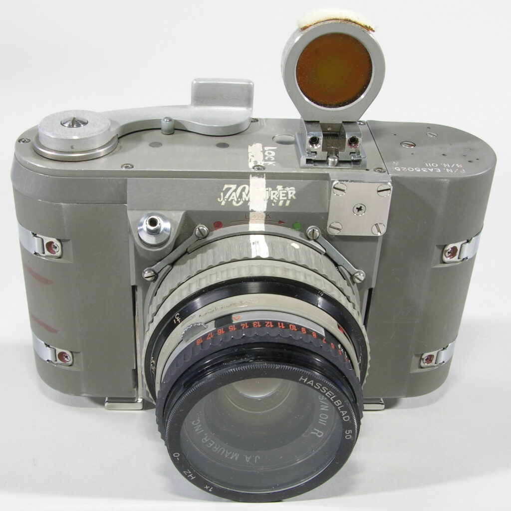 old grey camera with various controls on top and a big lens and