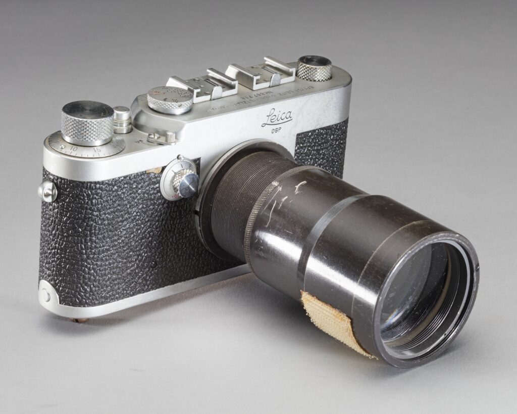 old silver metal and black leather camera with long black lens