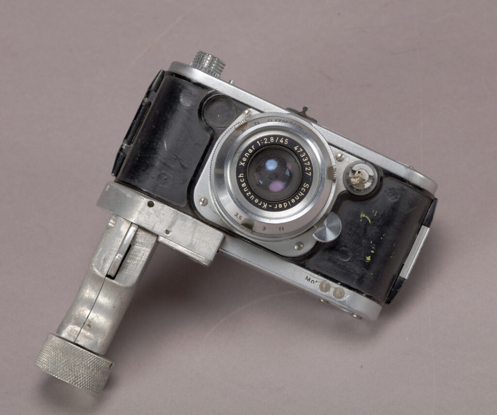 old silver metal and black leather camera with lens and handle underneath