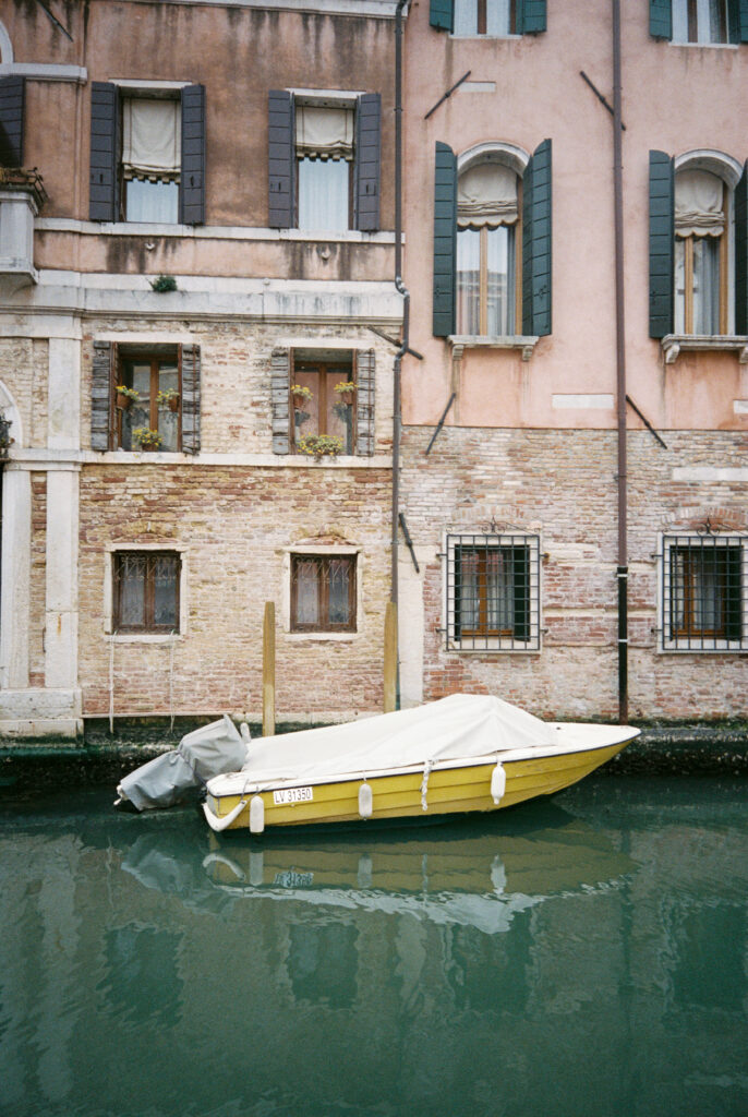 Canal boat in Venice, centre frame with townhouses in background.