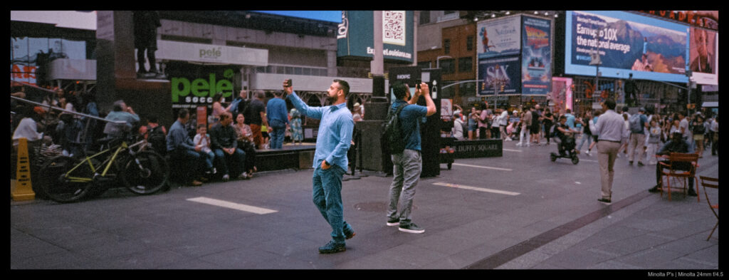 Two friends take photos back-to-back of Times Square.