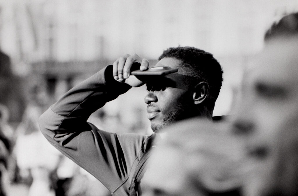 A man using his phone to block sun from his eyes