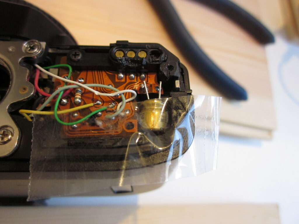 A photo showing the new capacitor held in place by tape prior to soldering