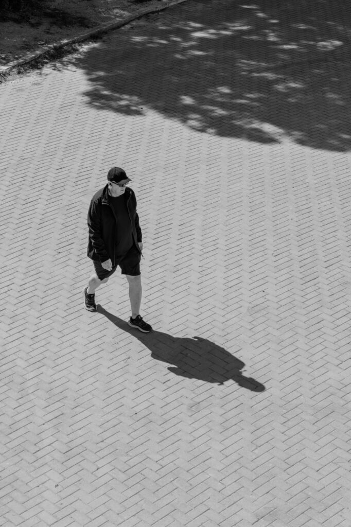 Aerial view of a man walking across herringbone-patterned pavement, casting a long shadow
